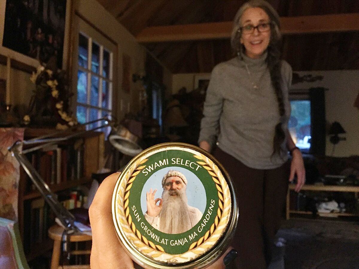 A can labeled Swami Select and depicting a white bearded man is held up in front of a woman standing in a room